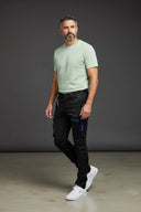 Frontansicht, nach vorne links ausgerichtetes männliches Modell  in der Bewegung, in der Eskotomic Winterreithose für Islandpferdereiter, lockere Passform, vor grauem Hintergrund, an der Hose sind zwei Taschen mit wasserdichtem blauem Reißverschlüssen und zwei weiteren Taschen für die Hände, optimal für Reiten und Arbeiten, schwarzer Softshellstoff.